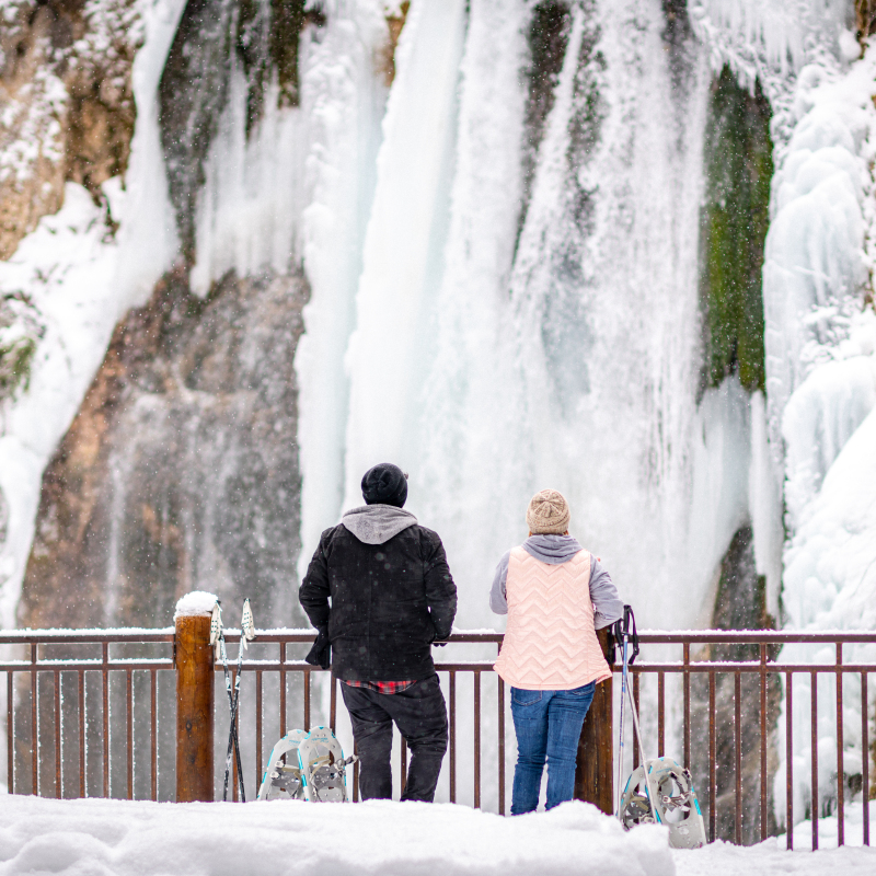 Couple snowshoeing - enjoying the view of Spearfish Waterfall in winter 