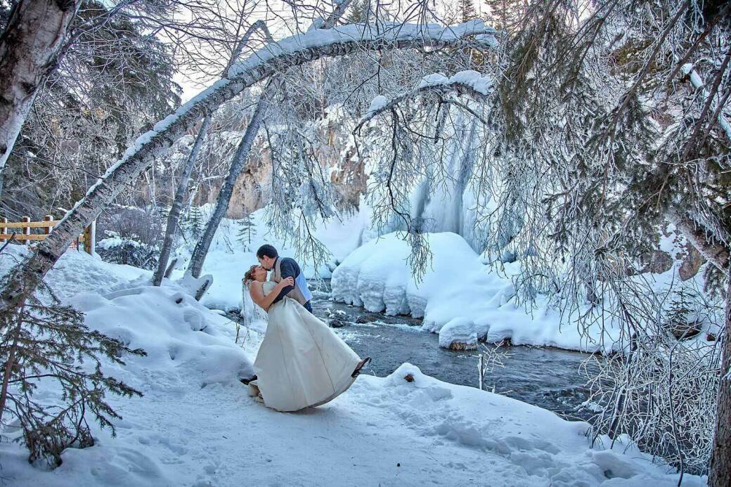 Winter Scene of Bride & Groom embracing in front of Spearfish Creek